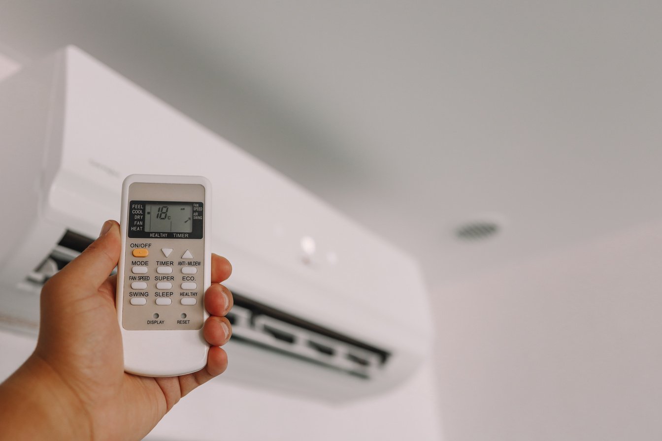 Hand is holding a remote control of air conditioner